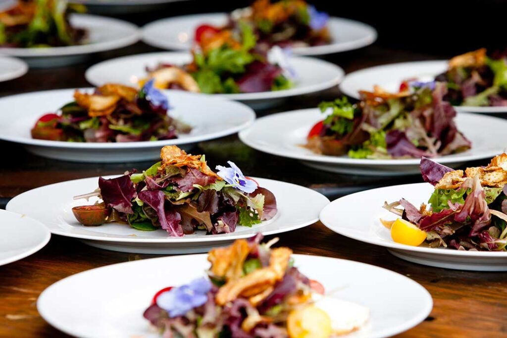 A group of people reviewing menus and discussing catering details around a table with sample dishes.