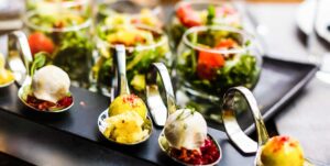 A colorful buffet table set with vegetarian dishes like salads, pasta, and roasted vegetables, with people serving themselves.