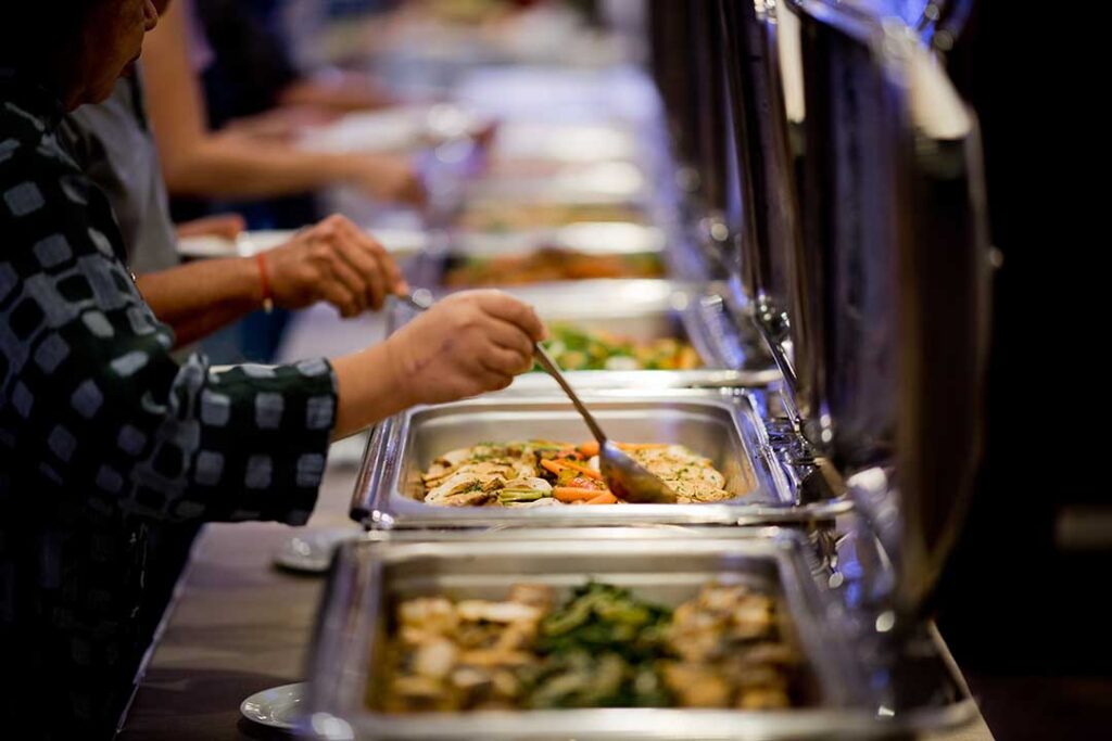 A kitchen table set with small plates of appetizers, salads, dips, and drinks ready for self-serve at a home gathering.