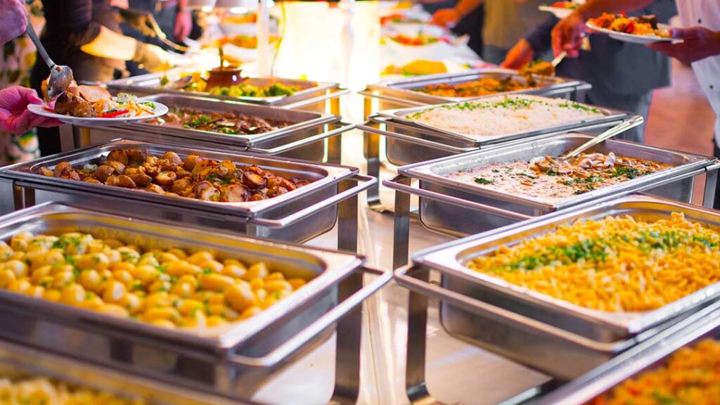 A group of people serving themselves from a buffet table at a casual indoor event.