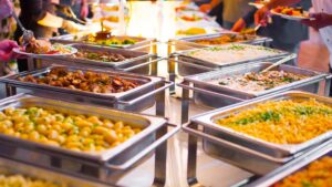 A group of people serving themselves from a buffet table at a casual indoor event.